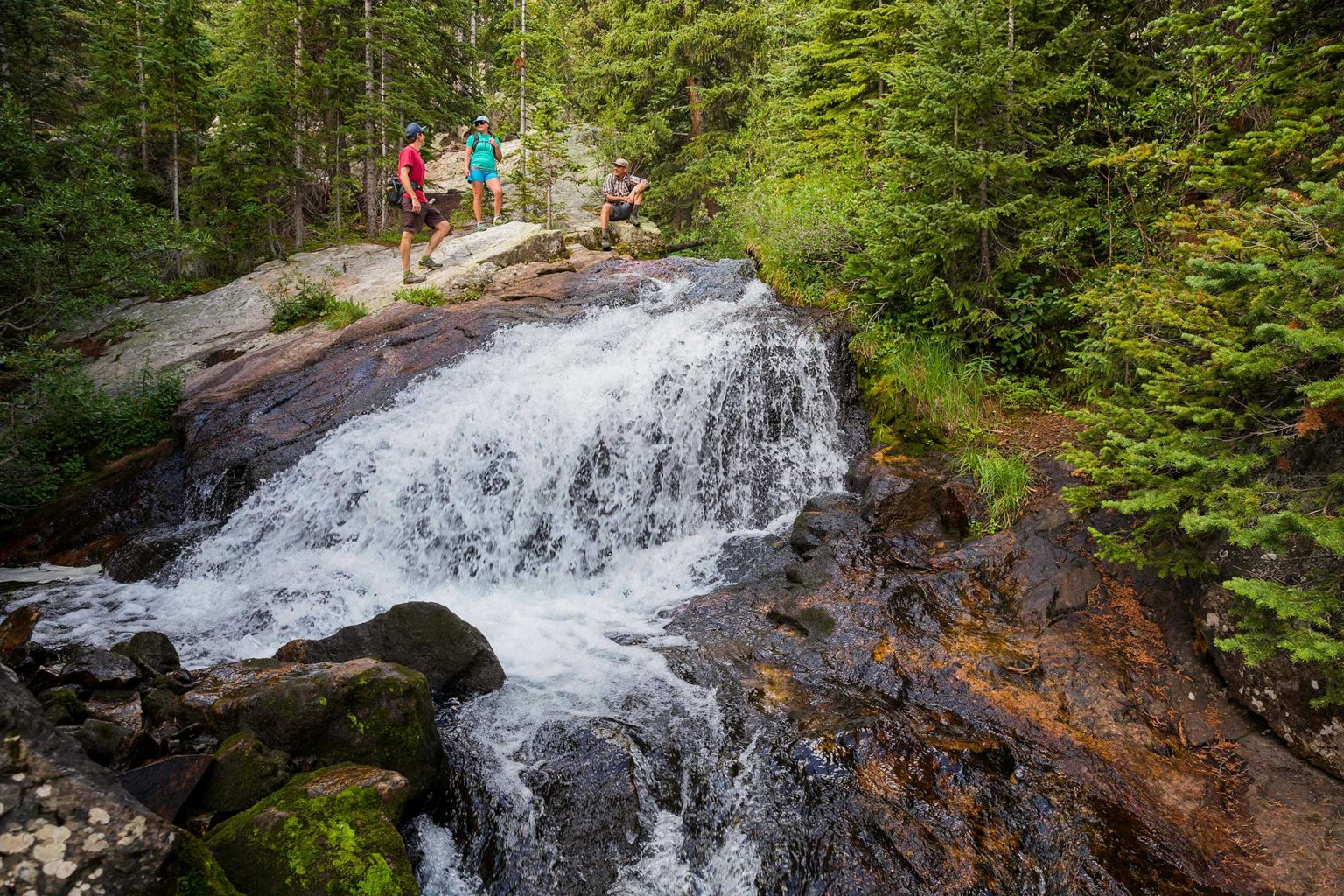 Hikers enjoy waterfall at McCulough Gulch