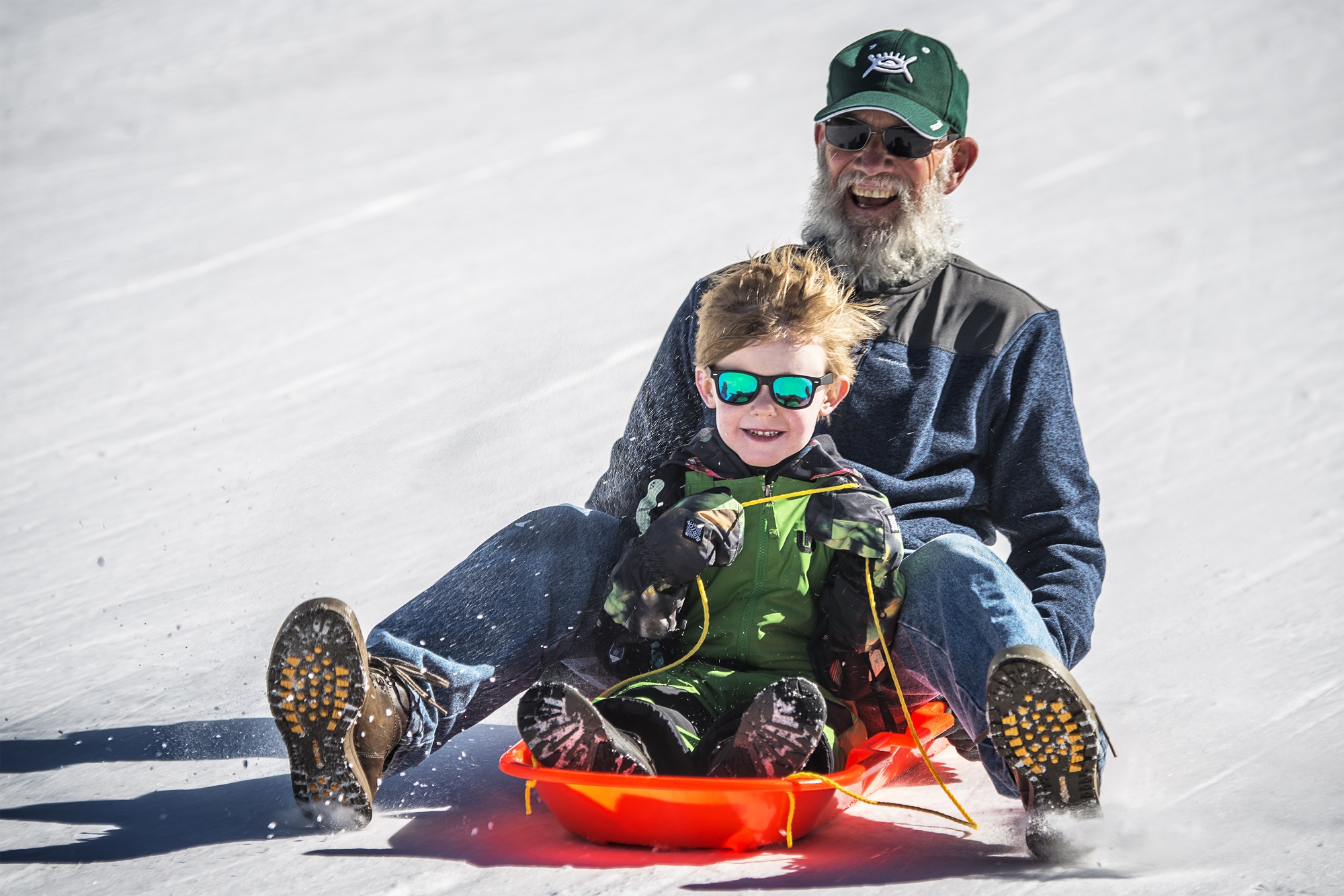 A grandpa and grandchild sledding at Breckenridge