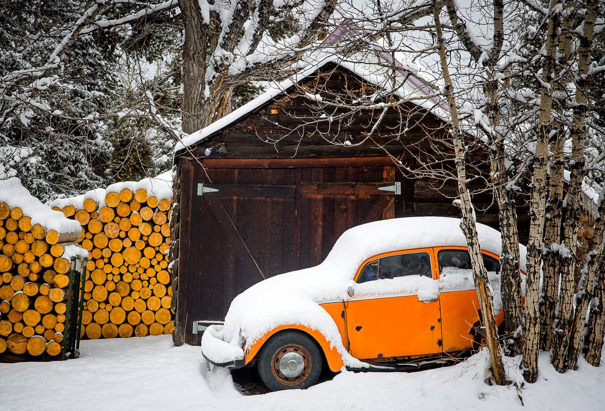 An orange Volkswagen beetle covered in snow