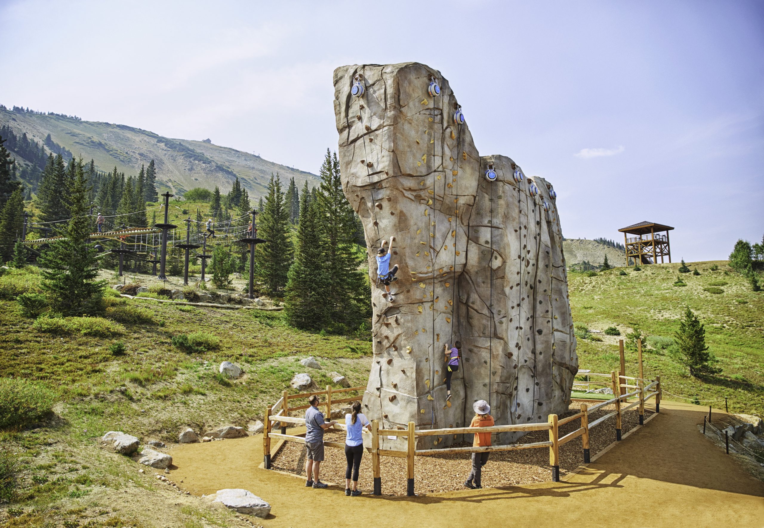 Children climbing up a rock climbing wall at the Epic Discovery on a sunny summer day in Breckenridge.