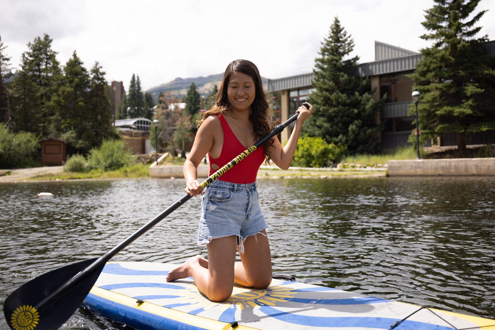 A woman stand-up paddleboarding on Maggie Pond on a sunny summer day in Breckenridge.