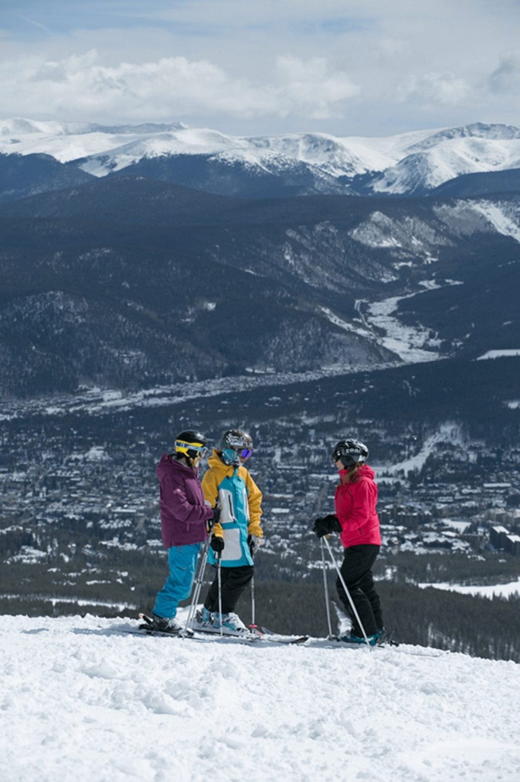 Three Friends chatting at the top of a ski run enjoying a sunny Breckenridge day