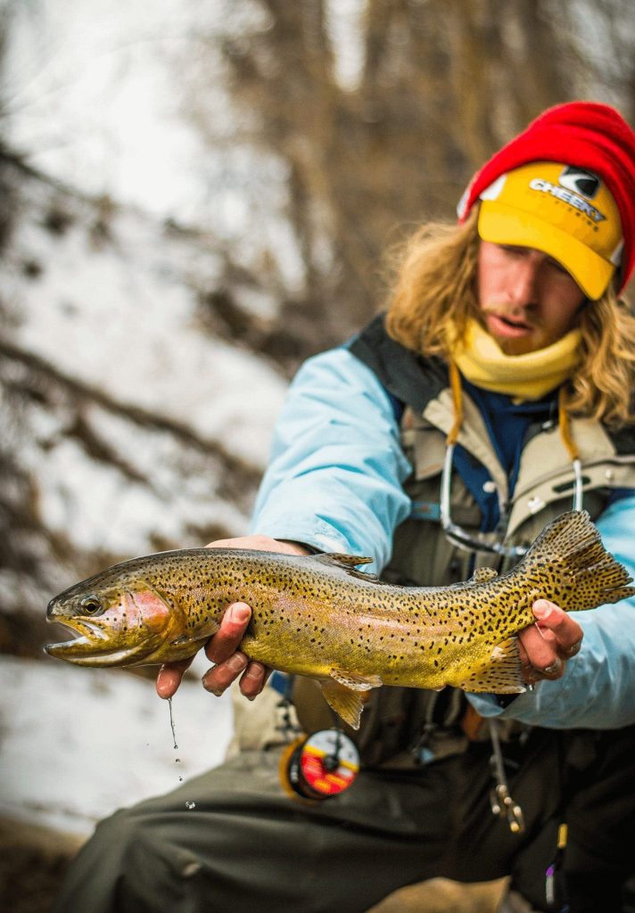 A man holding his trout catch during wintertime in Breckenridge