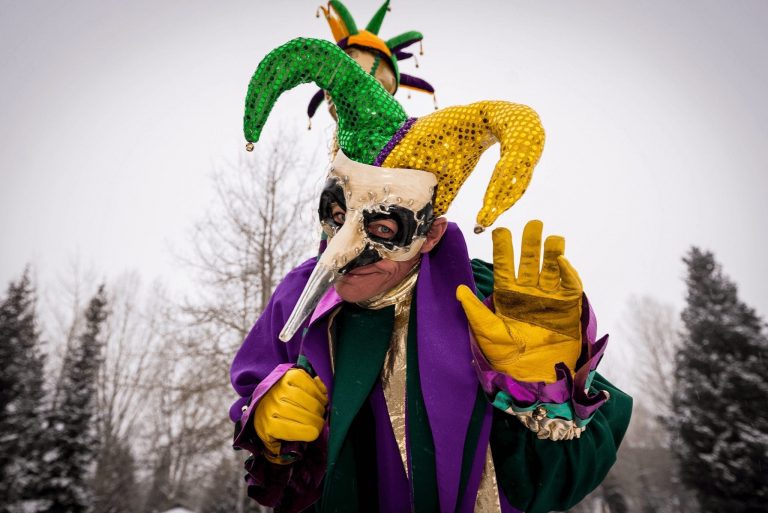 Man dressed in Mardi Gras mask and colorful costume during Breckenridge parade