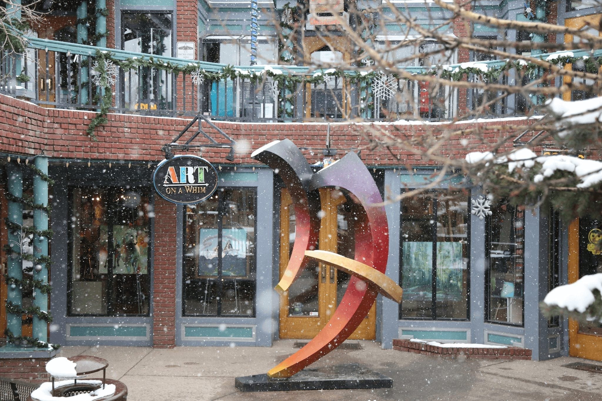 Snow falling during winter in front of an art gallery and sculpture.