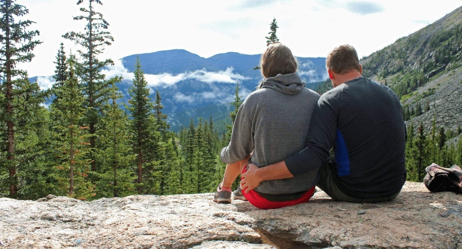 A seated couple looking at the view from the McCollough Gulch trail in Breckenridge