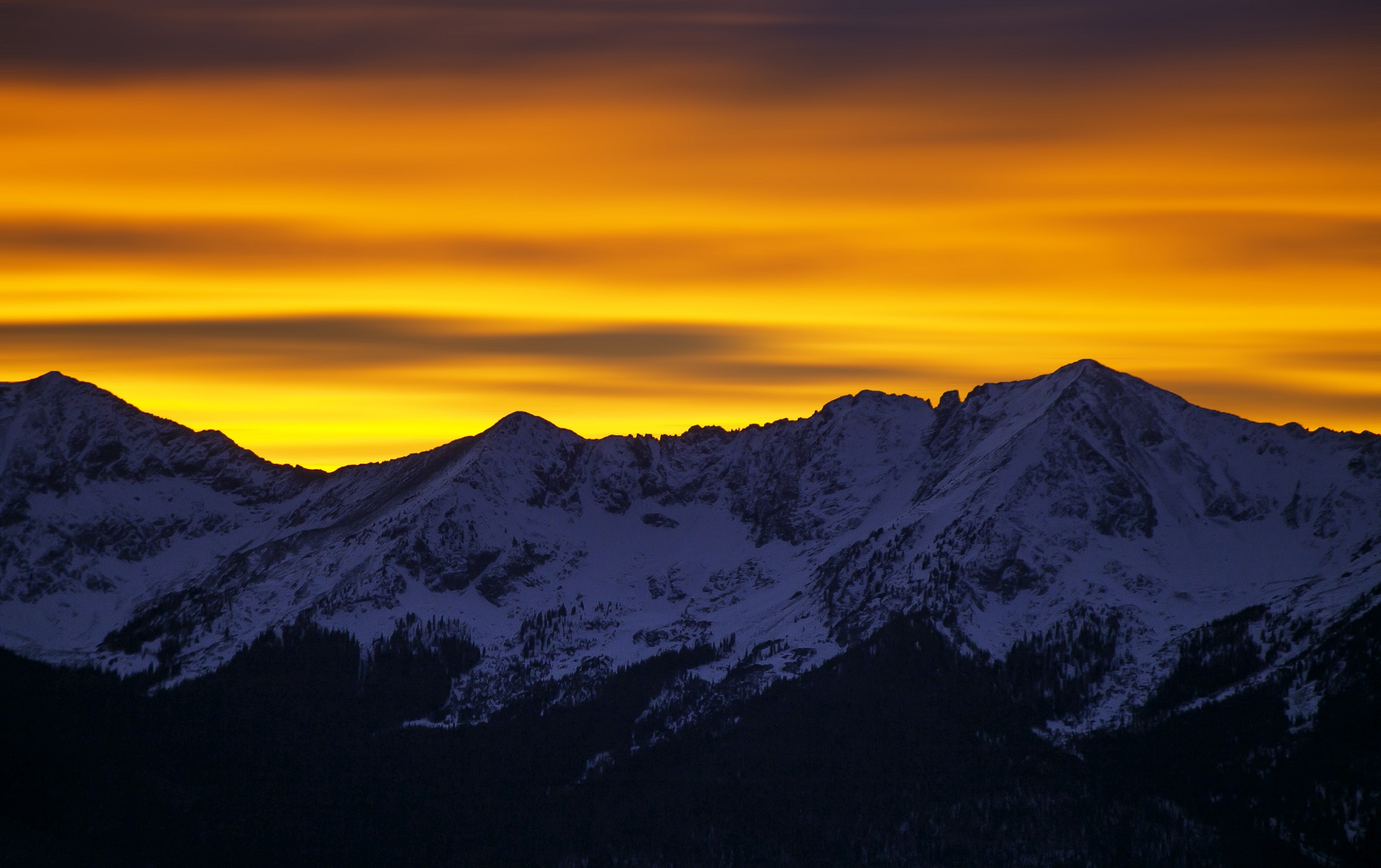 A layered orange and yellow sunset above the mountains