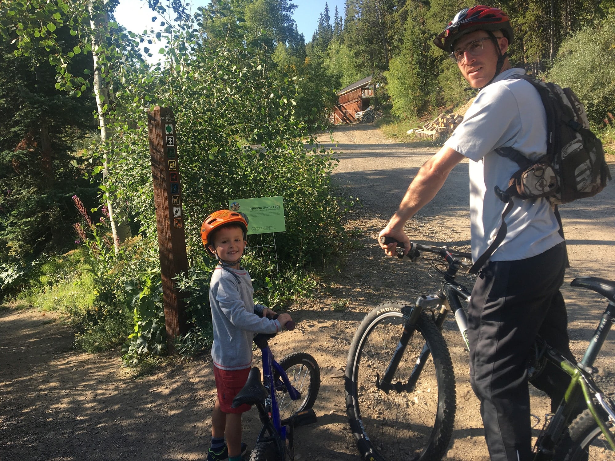 Kid mountain biking on trail with his dad in Breckenridge