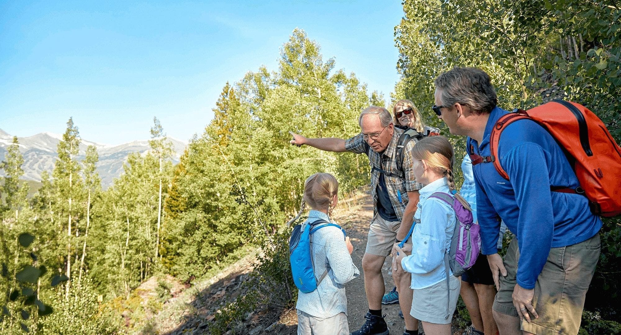 Family Hiking in Breckenridge Colorado with grandpa pointing to Breckenridge Ski Resort.
