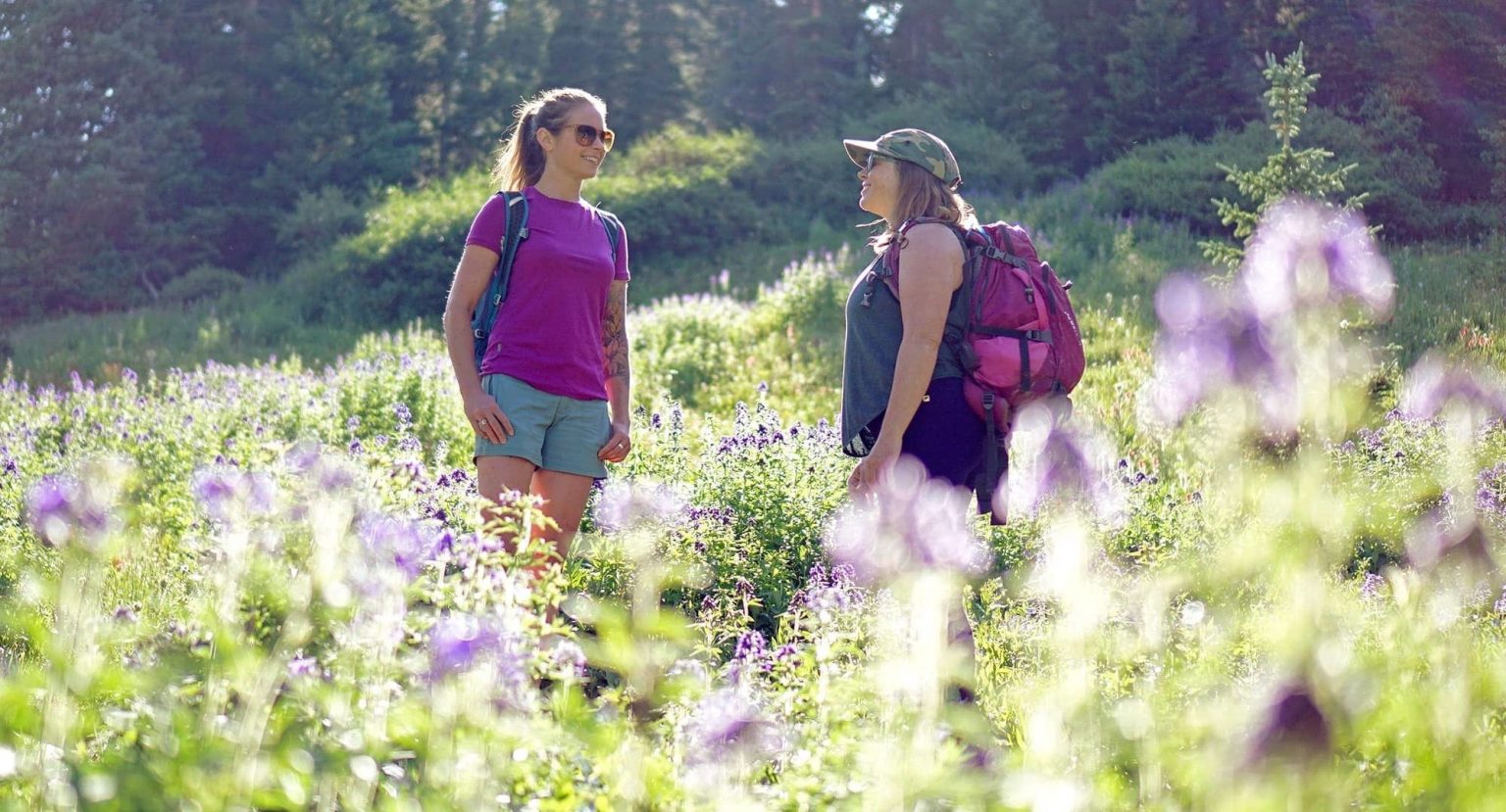 Two women talking in wildflowers - photo by Louie Traub