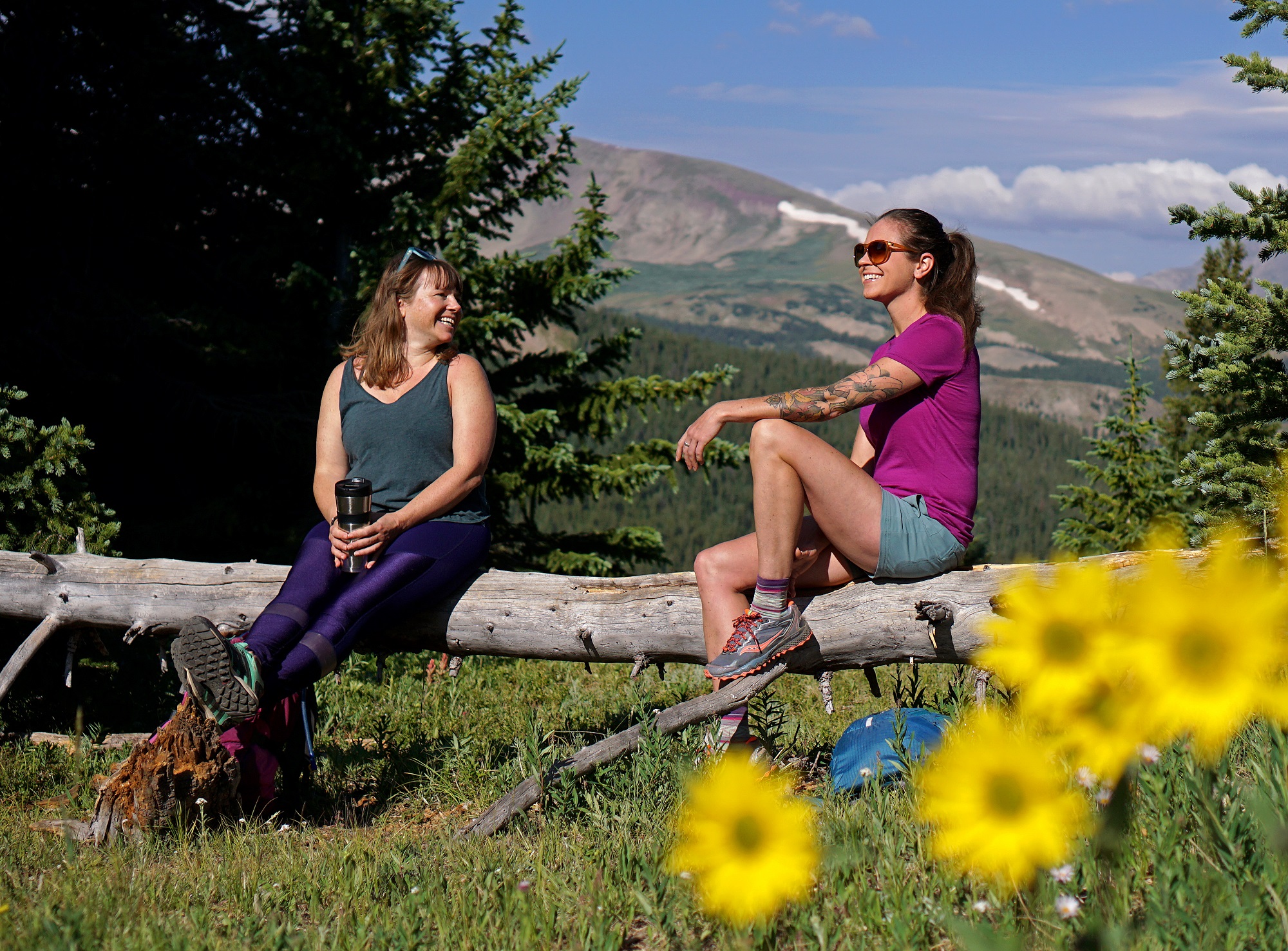 Women chatting while sitting on a log in the sunshine at Breckenridge