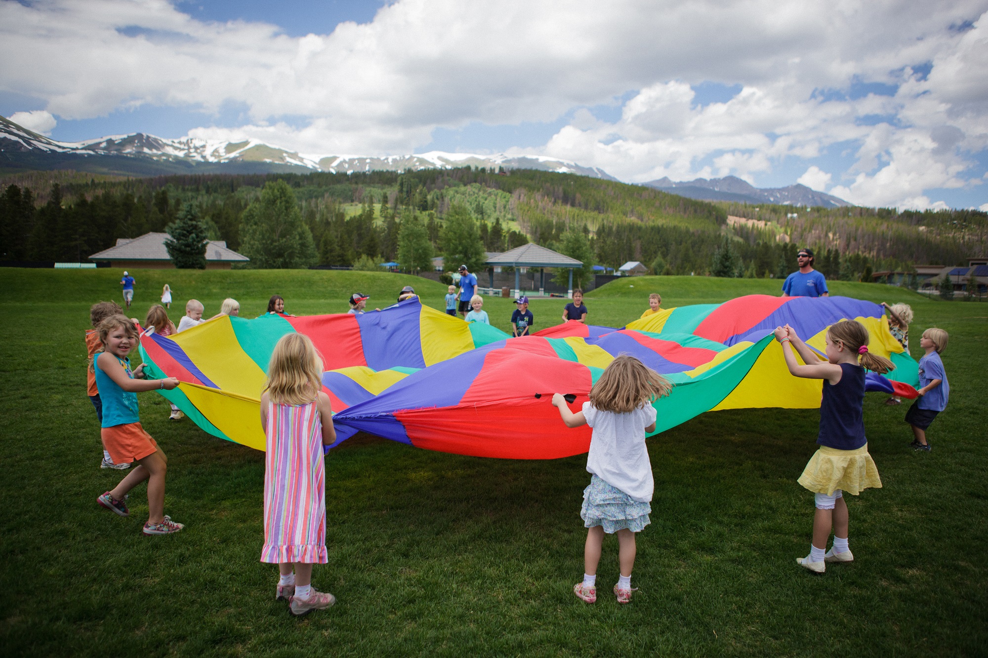 Kids playing with a parachute at Breckenridge Mountain Day Camp on the lawn.