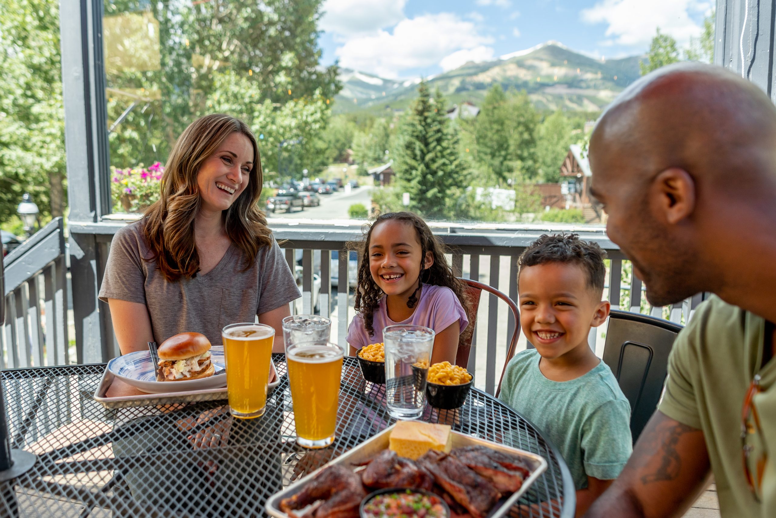 A family of four sits down at a patio in Breckenridge to eat BBQ. 