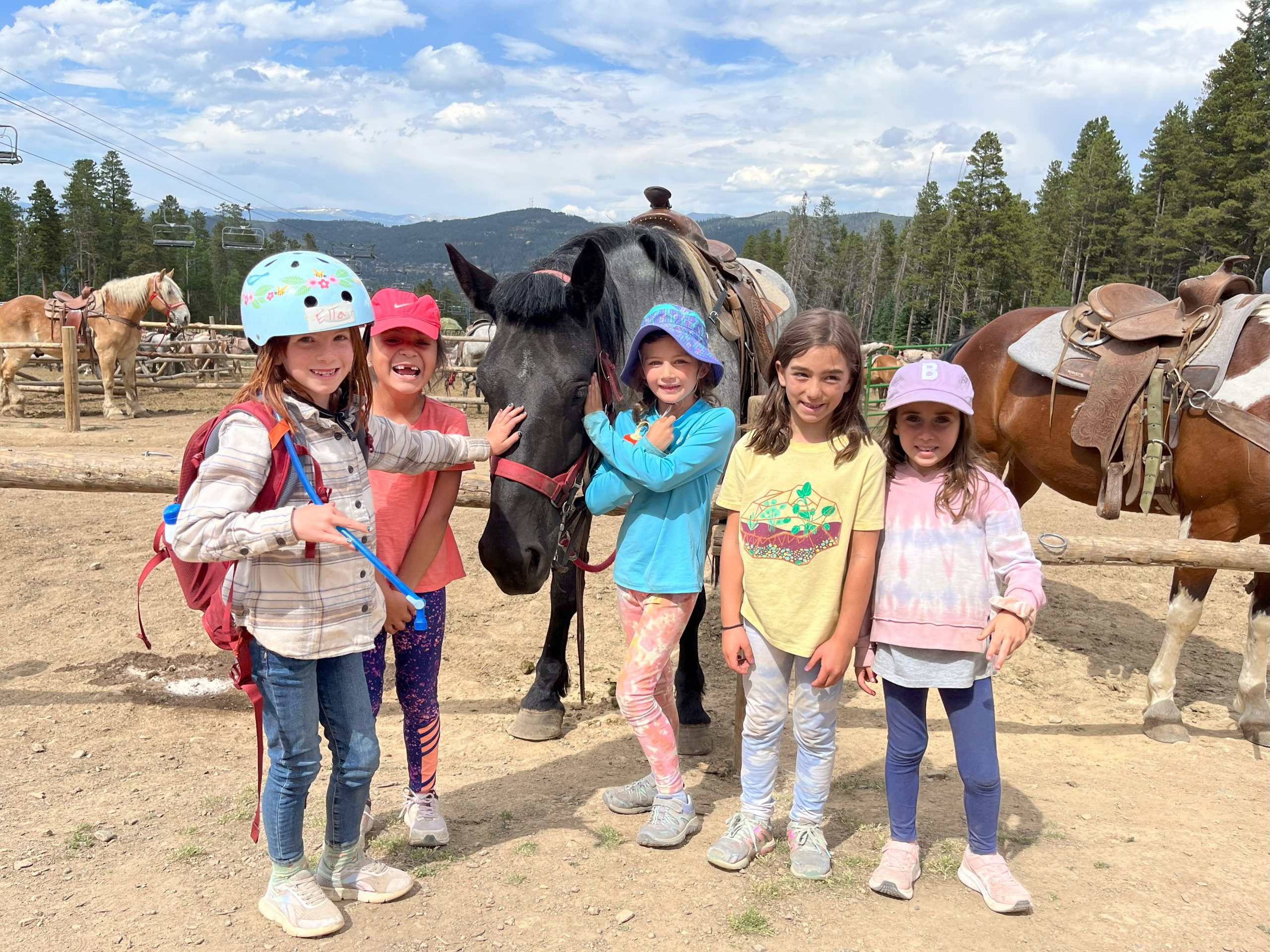 Children wearing helmets smiling while learning about horses and horse riding in Breckenridge