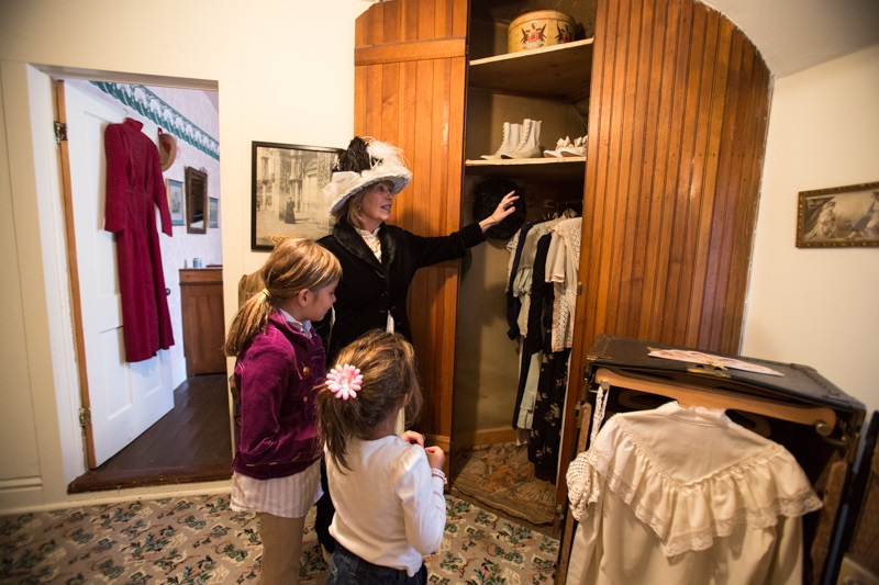A Breckenridge Heritage Alliance Tour Guide shows a historical bedroom to a family.
