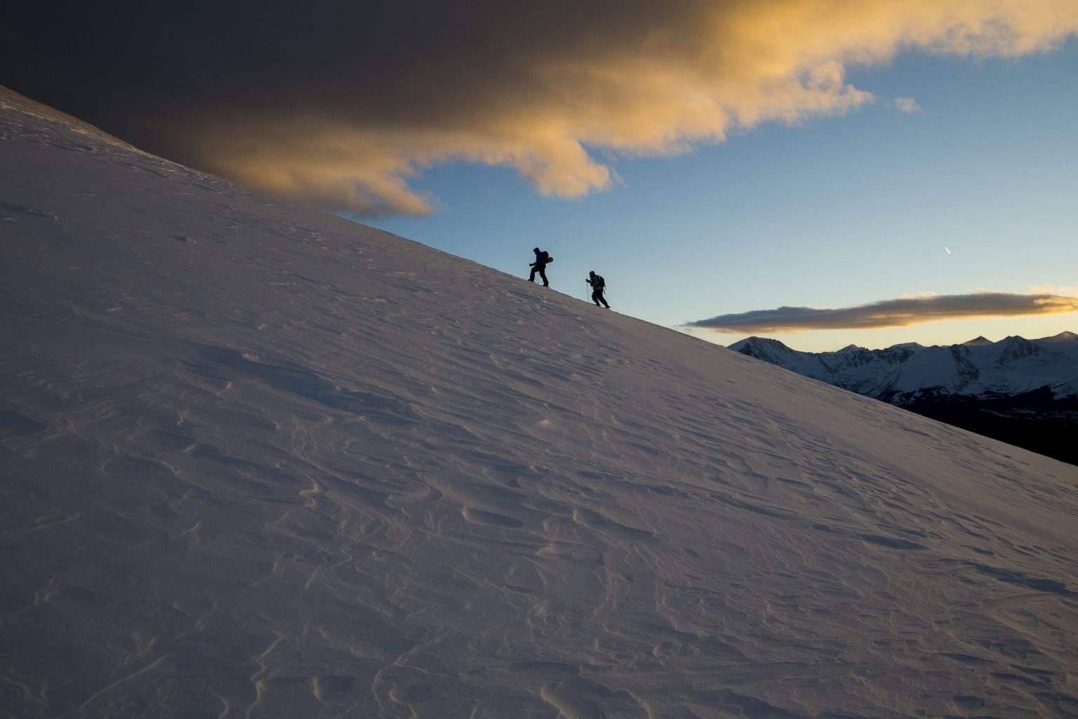 silhoutte of two people climbing a slope