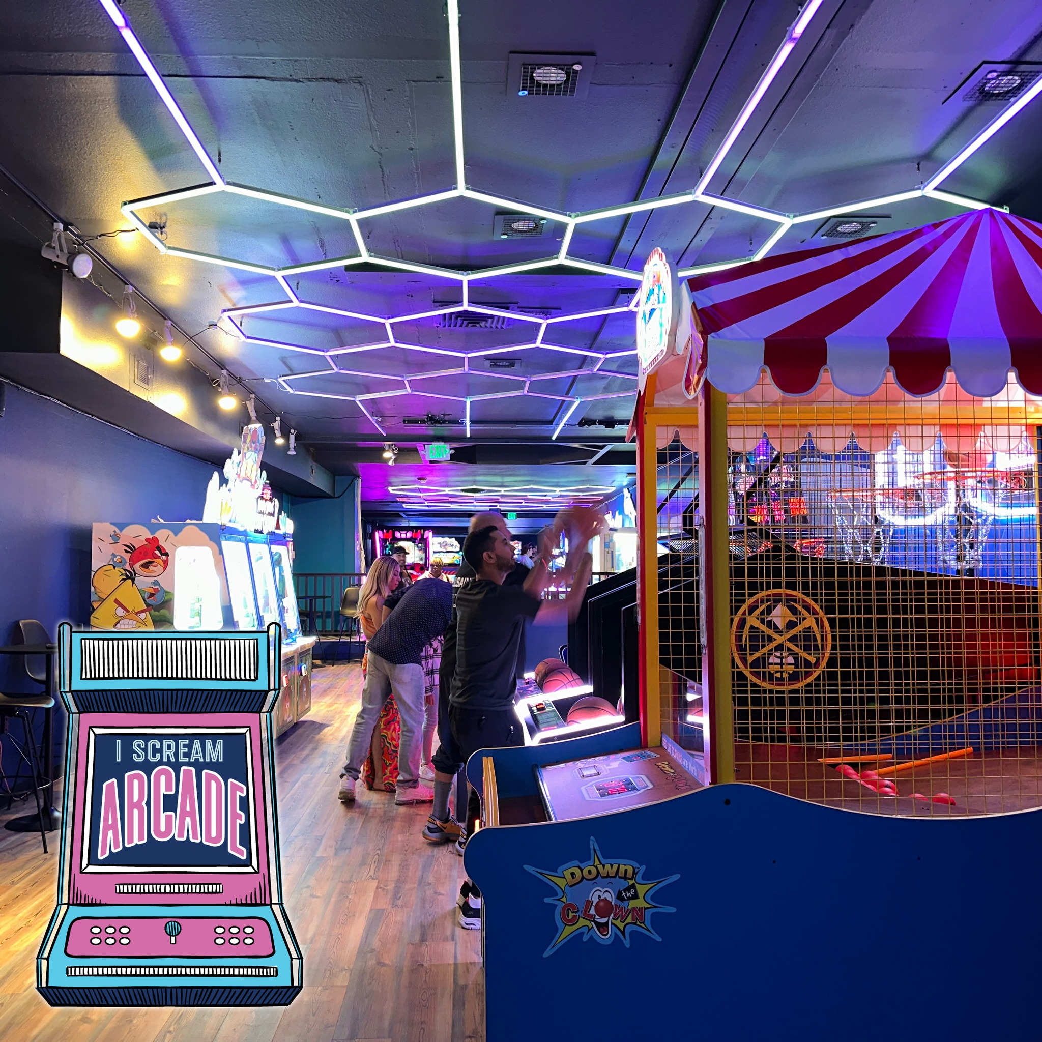 A look inside I Scream Arcade with honey-comb neon lights on the ceiling and dozens of arcade games to choose from, including first-person games, basketball and skee ball, and others. 