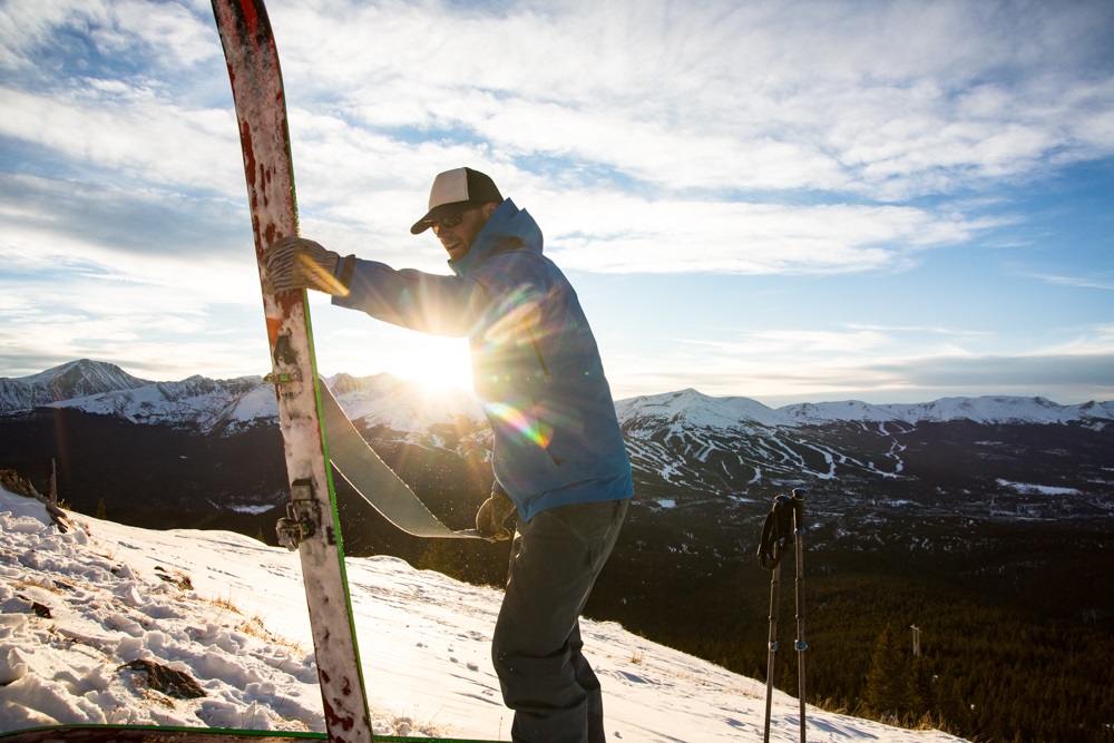 man preparring skis on a slope