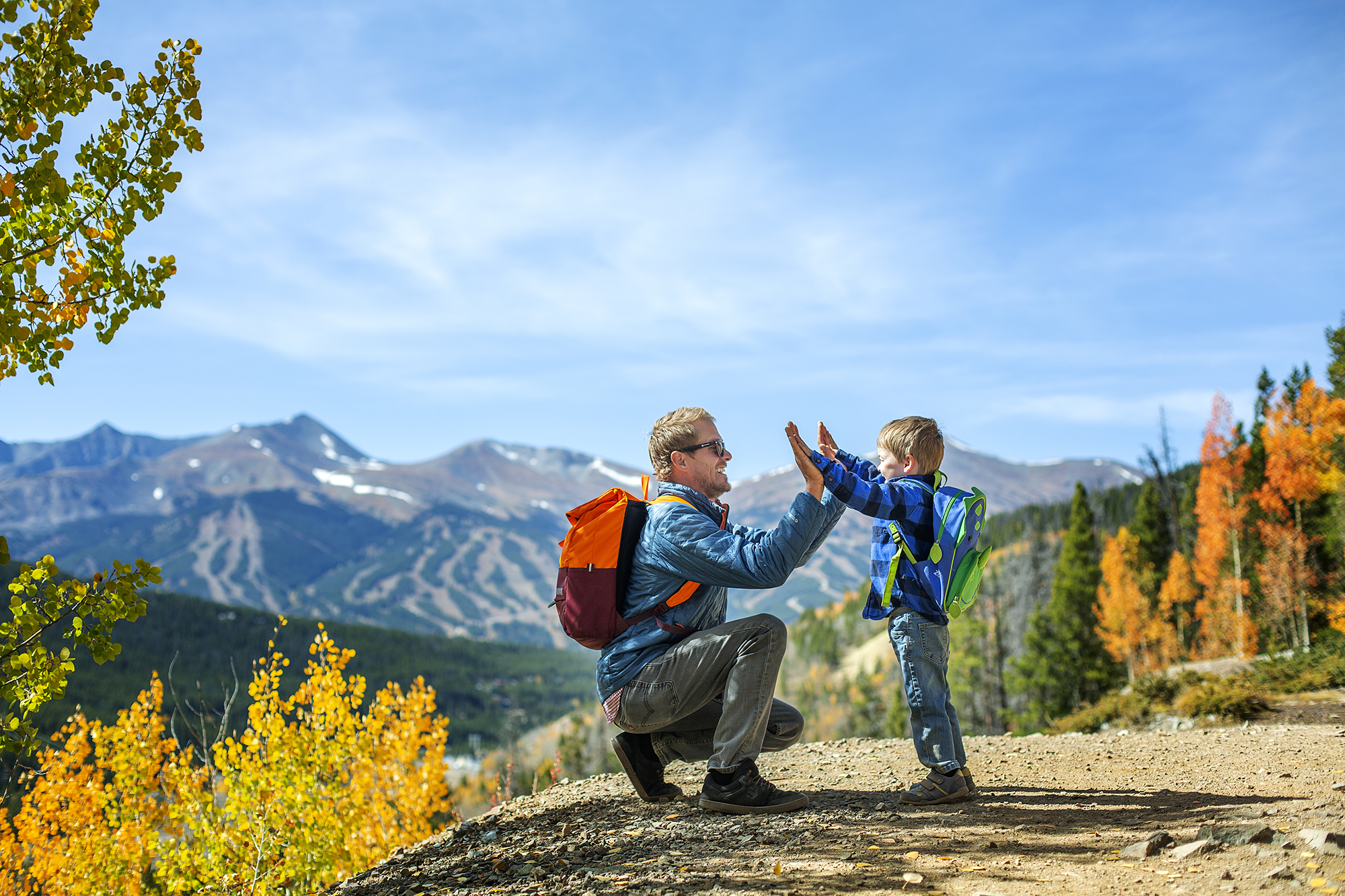 A father high fiving his son while hiking in Breck