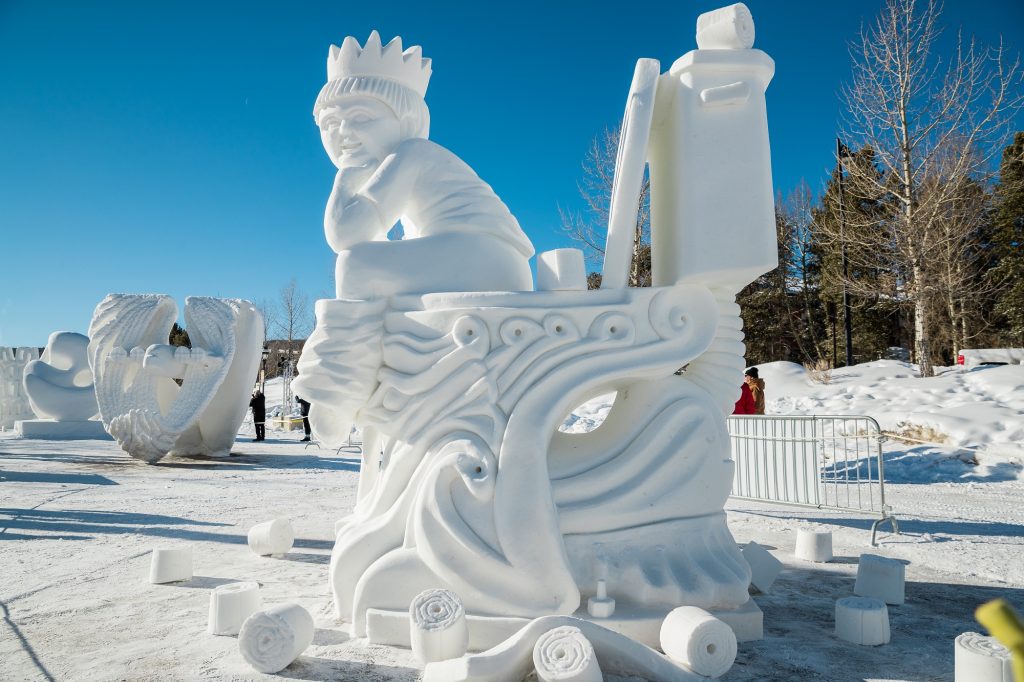 ornate snow sculpture of a kid on a toilet