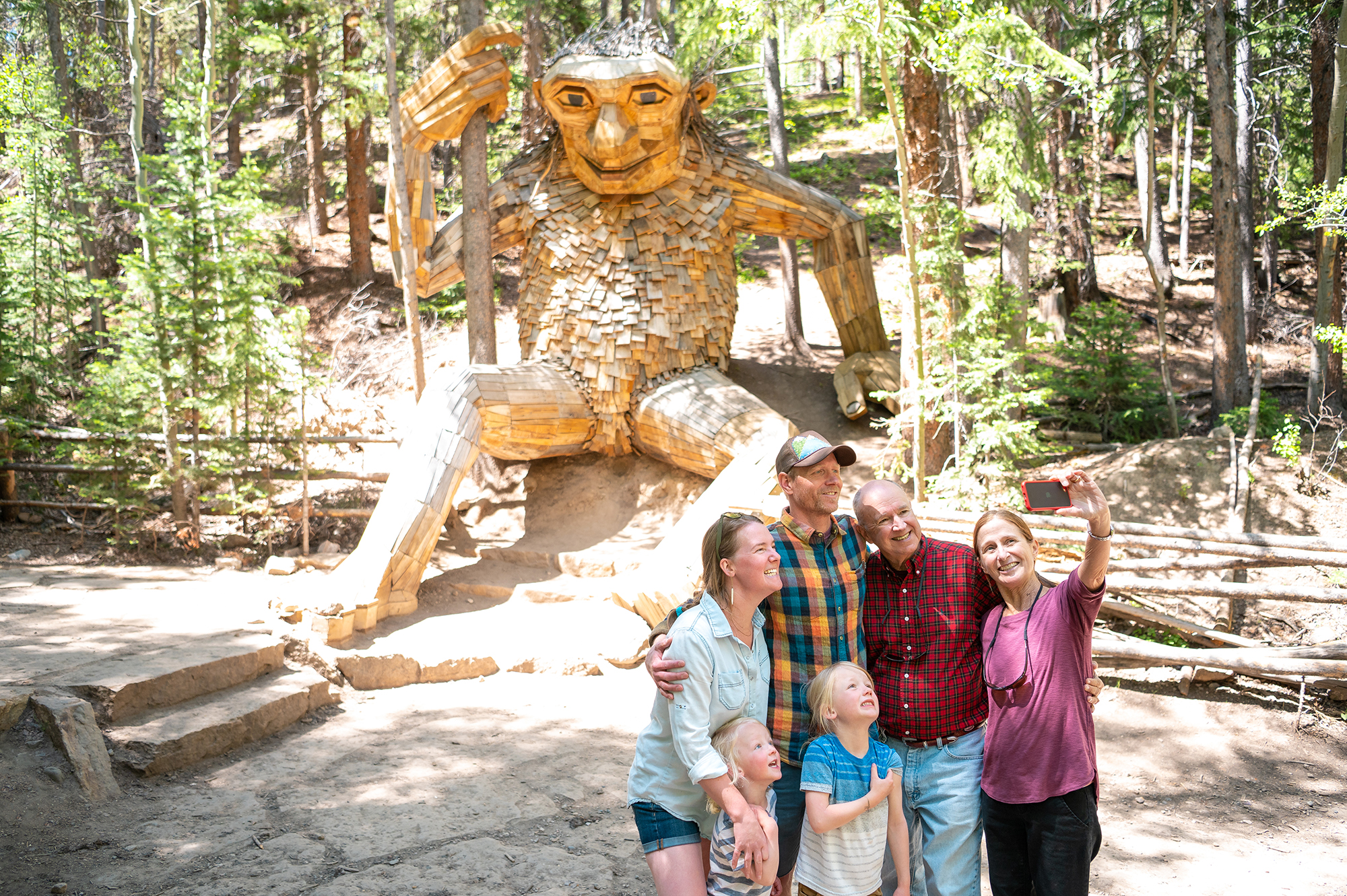 family taking a group photo in front of a wood sculpture
