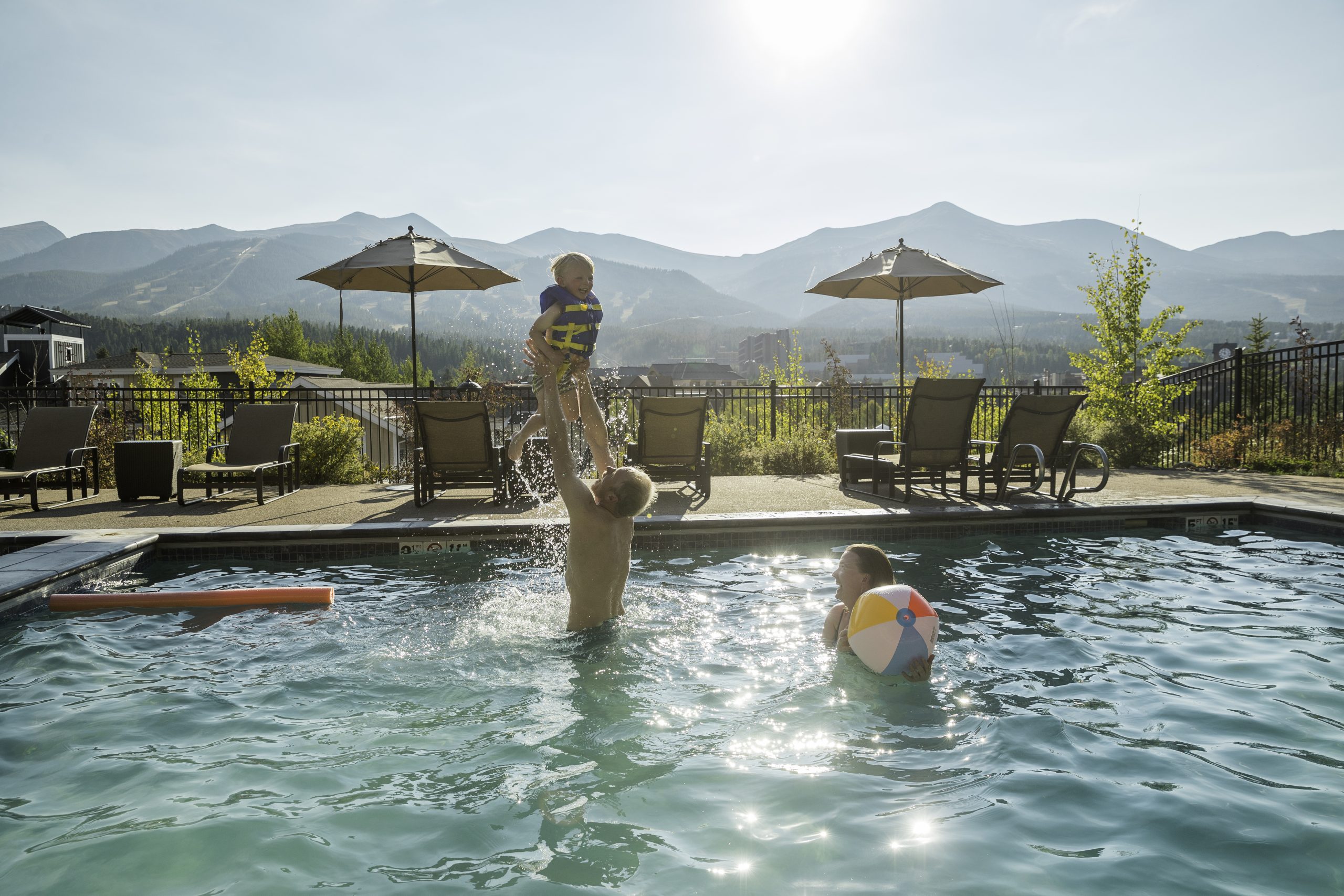 family playing in pool with mountains in background