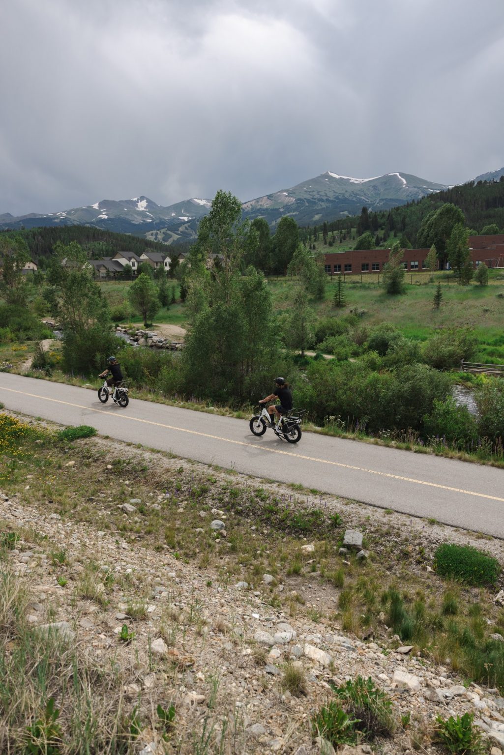 Two people biking on electric bikes on the Rec Path through Breckenridge on an overcast day.