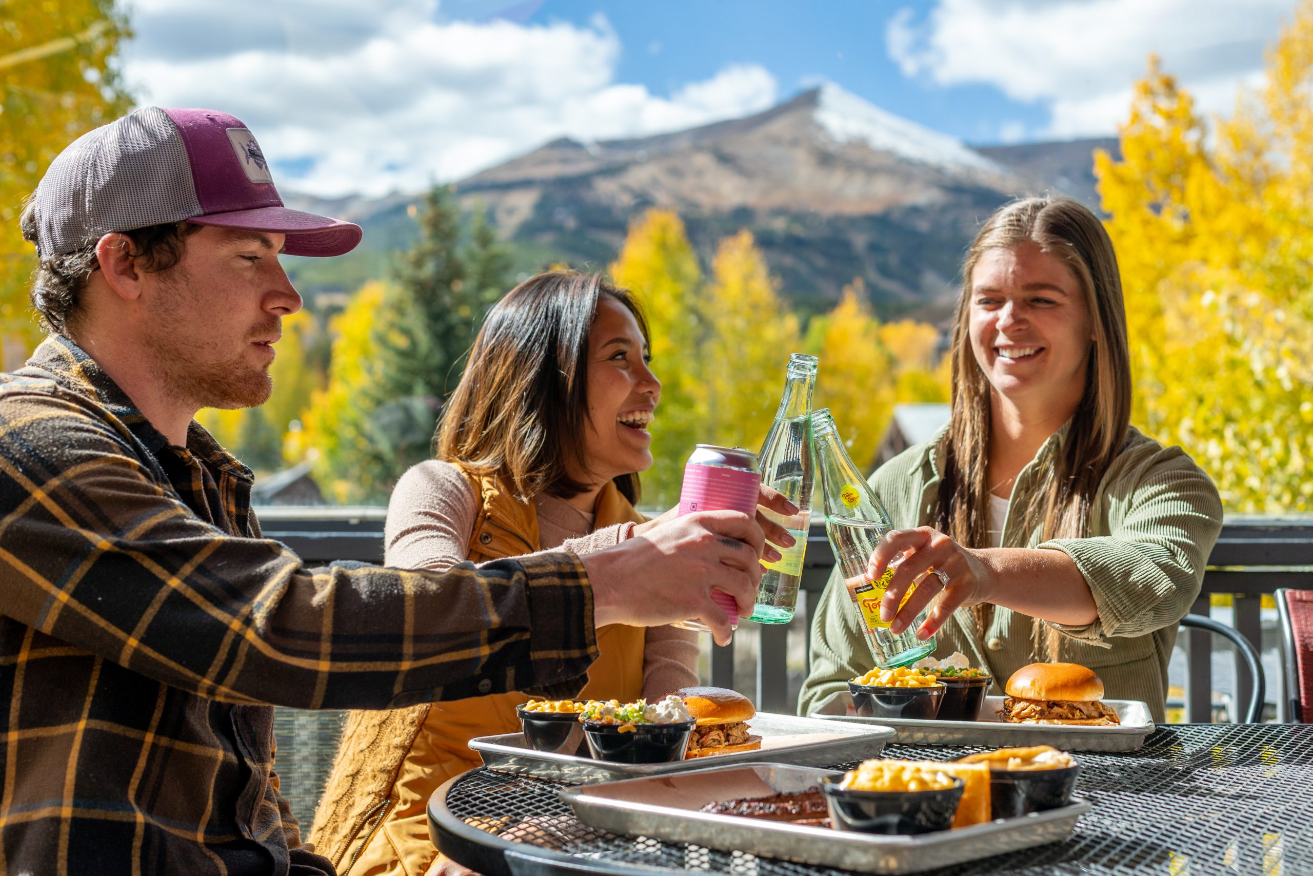 Three friends enjoying lunch on a patio during the colorful fall season in Breckenridge.