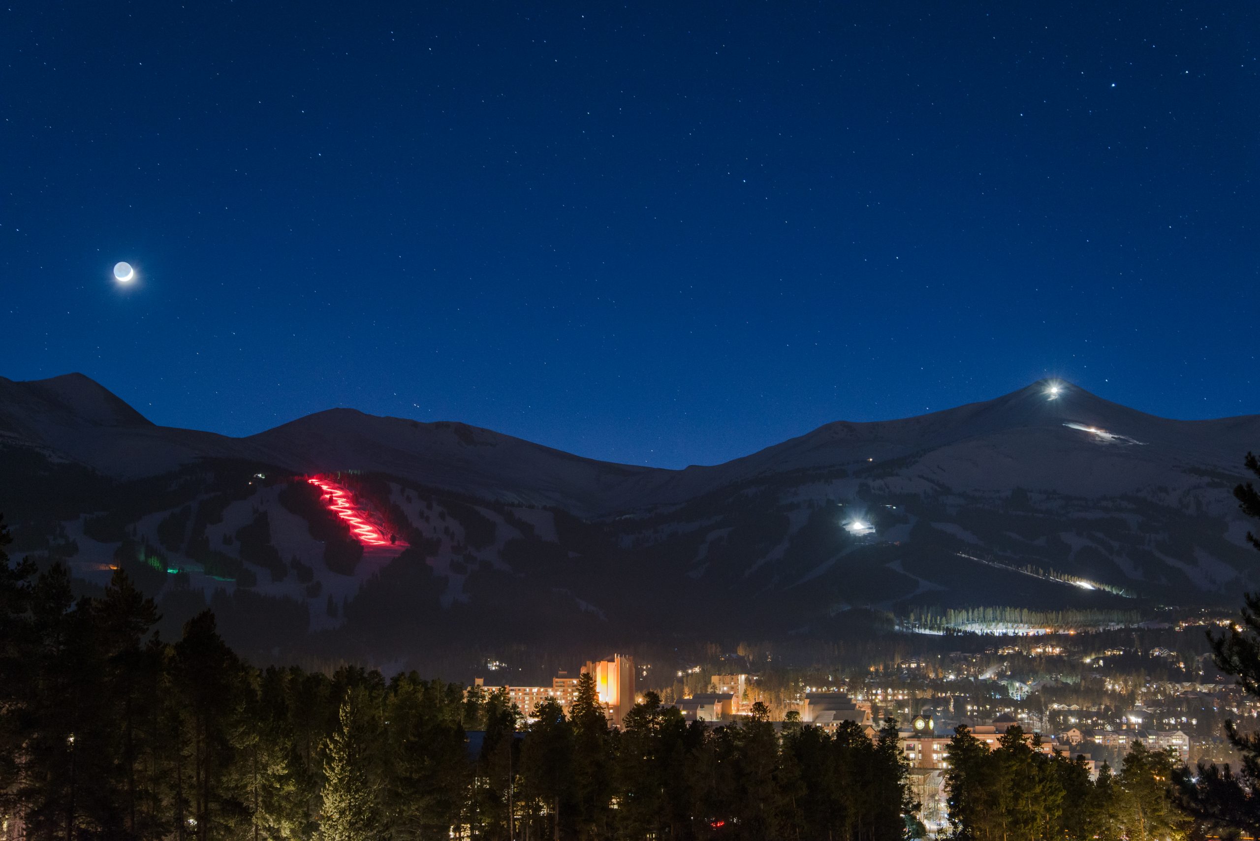 Mountain silhouette and a full moon at night.